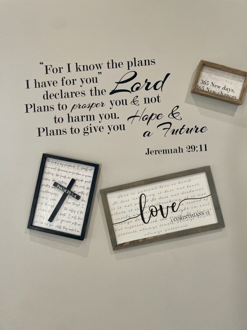 A wall with some framed pictures and bible verses